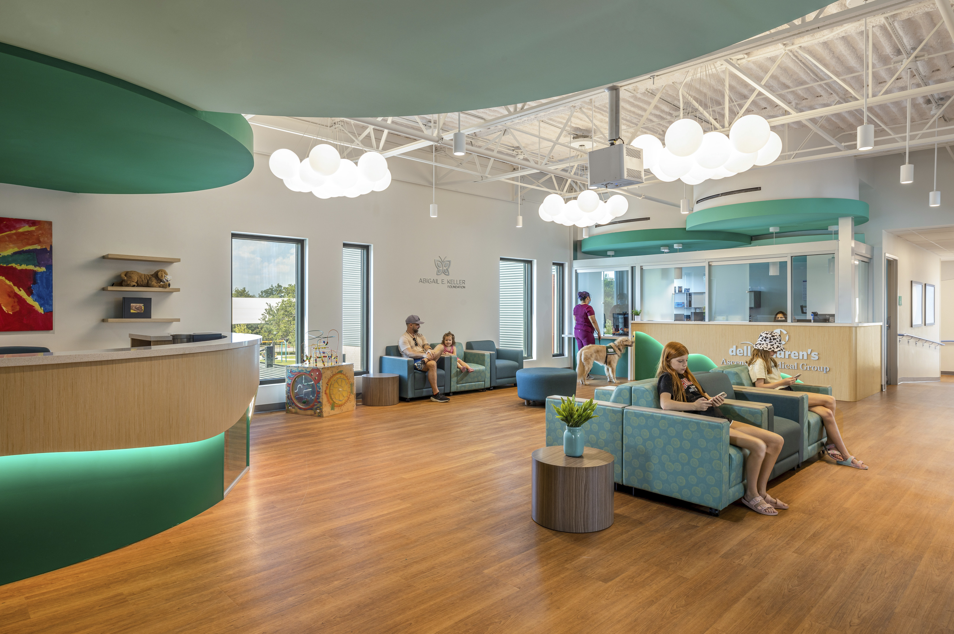 A bright waiting area with teal and wooden accents featuring comfortable seating and playful decor at a healthcare facility. 