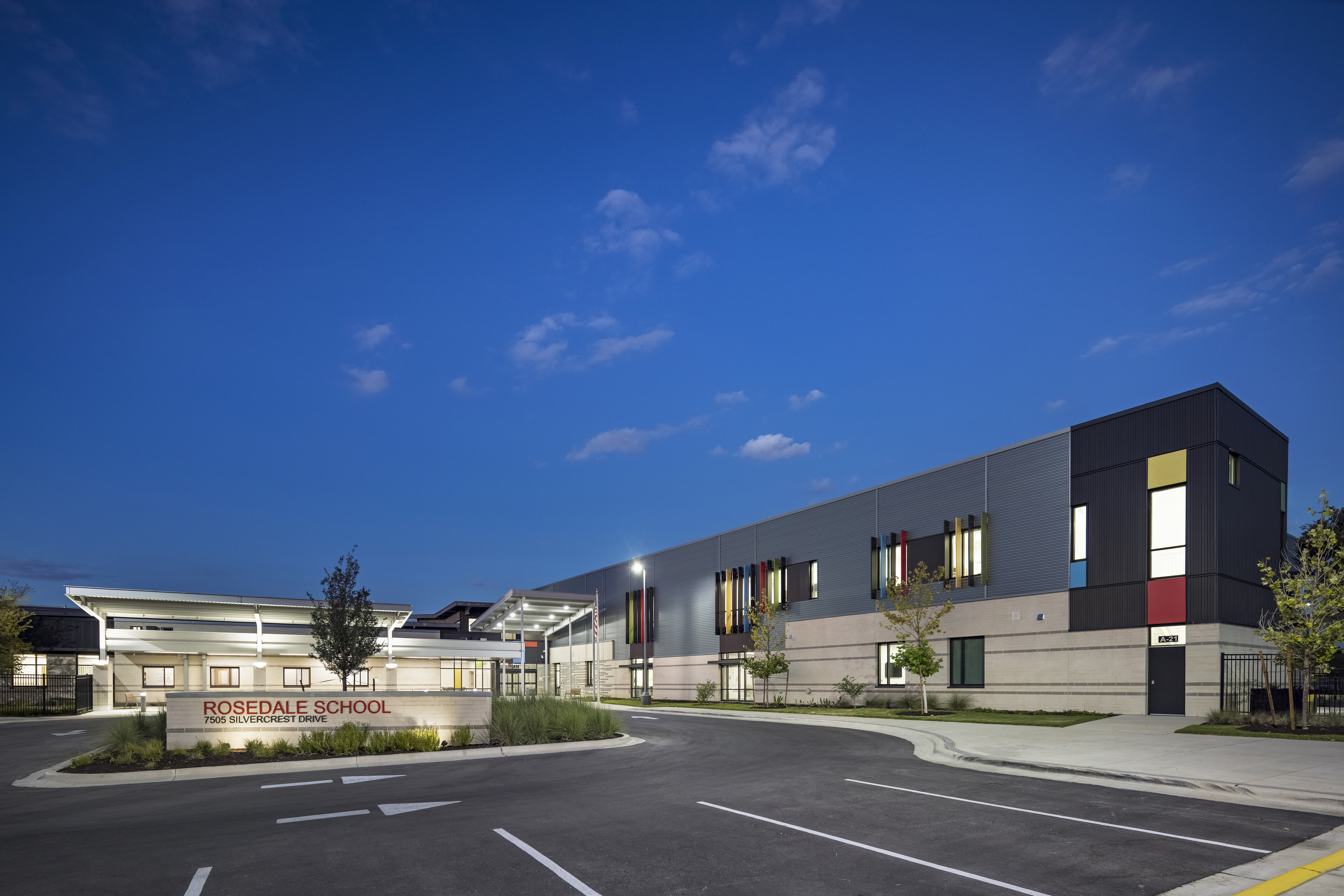 The Rosedale School's modern building's exterior illuminated at night, showcasing sleek lines and contemporary design against a dark sky.