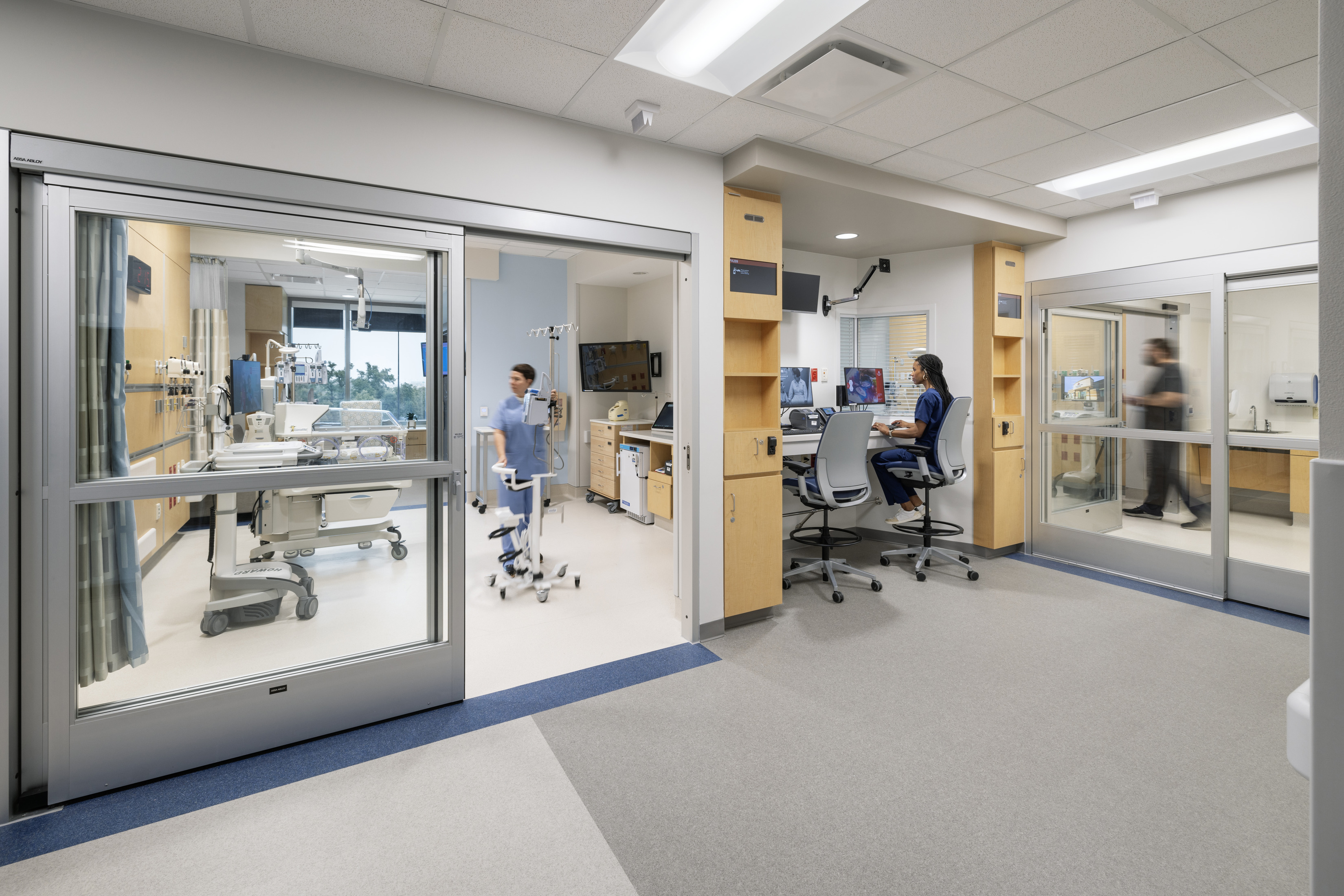 A modern hospital ICU with patient rooms, medical staff, and a central monitoring station.