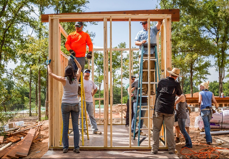 Several people are building a tiny home outside on a beautiful day.