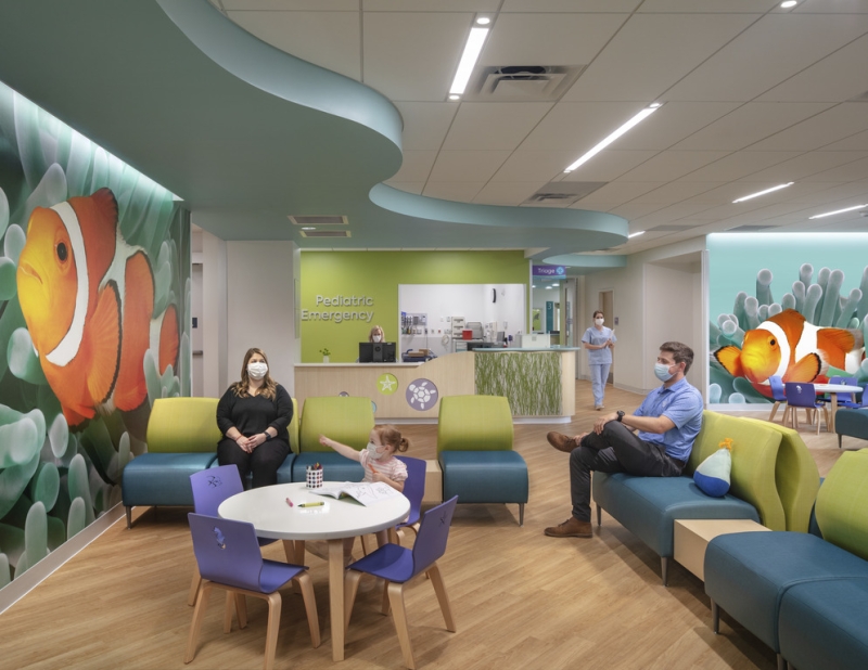 Pediatric patient and their guardians sitting inside of a medical center lobby 